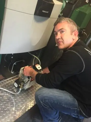 A technician working underneath a boiler during a service call